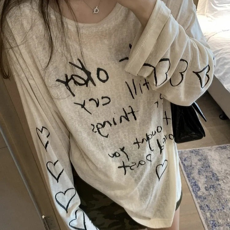 Kvinnors avslappnad oversized topp med avskuren axel design och konstnärlig text Mirla-Eva Jonsson