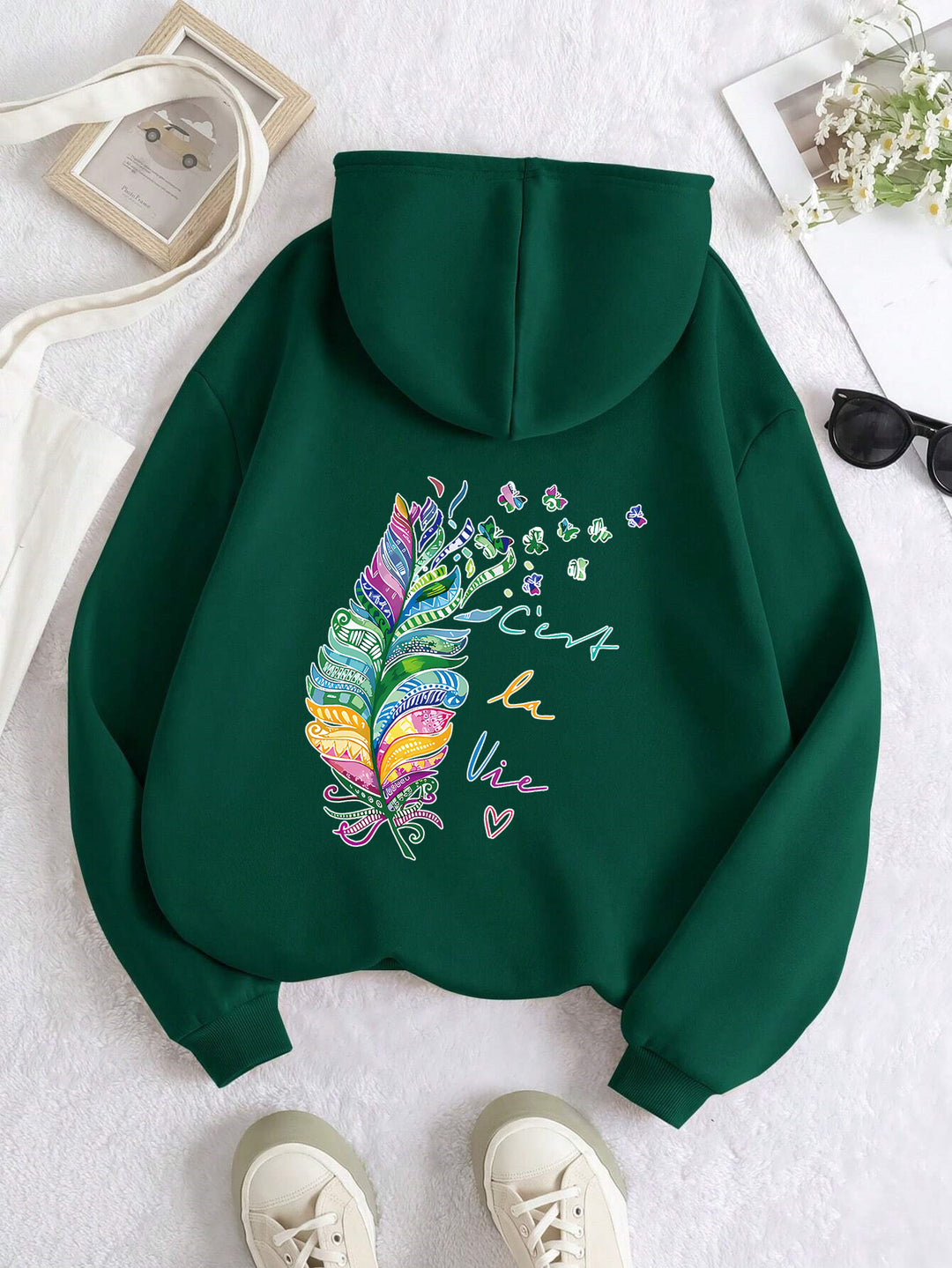 Kvinnors avslappnade hoodie med färgglad fjäderdesign och inspirerande text Mirla-Eva Jonsson